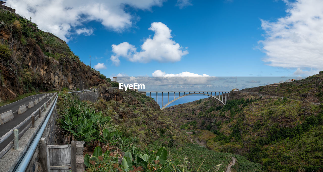 sky, cloud, nature, mountain, environment, landscape, travel, architecture, travel destinations, scenics - nature, transportation, plant, land, built structure, no people, beauty in nature, water, tourism, bridge, mountain range, tree, road, outdoors, city, panoramic, blue, day, tranquility, mountain pass, rail transportation, tranquil scene