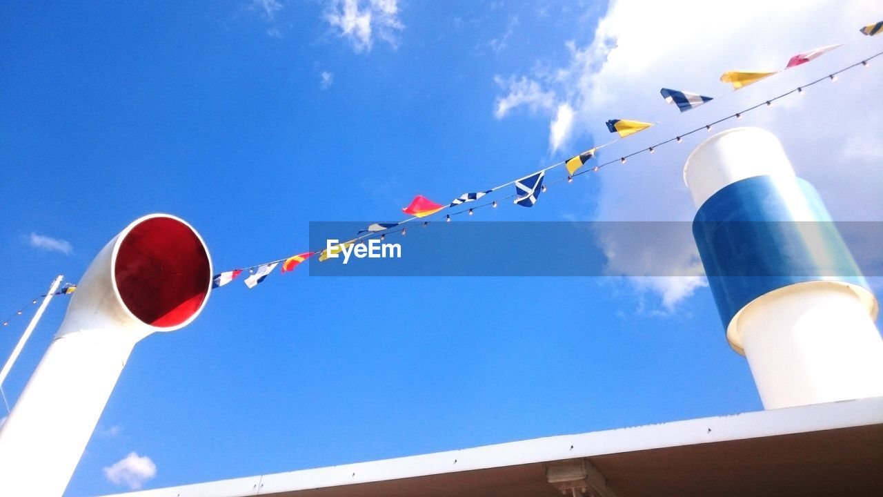 Low angle view of butting flag on smoke stacks against sky