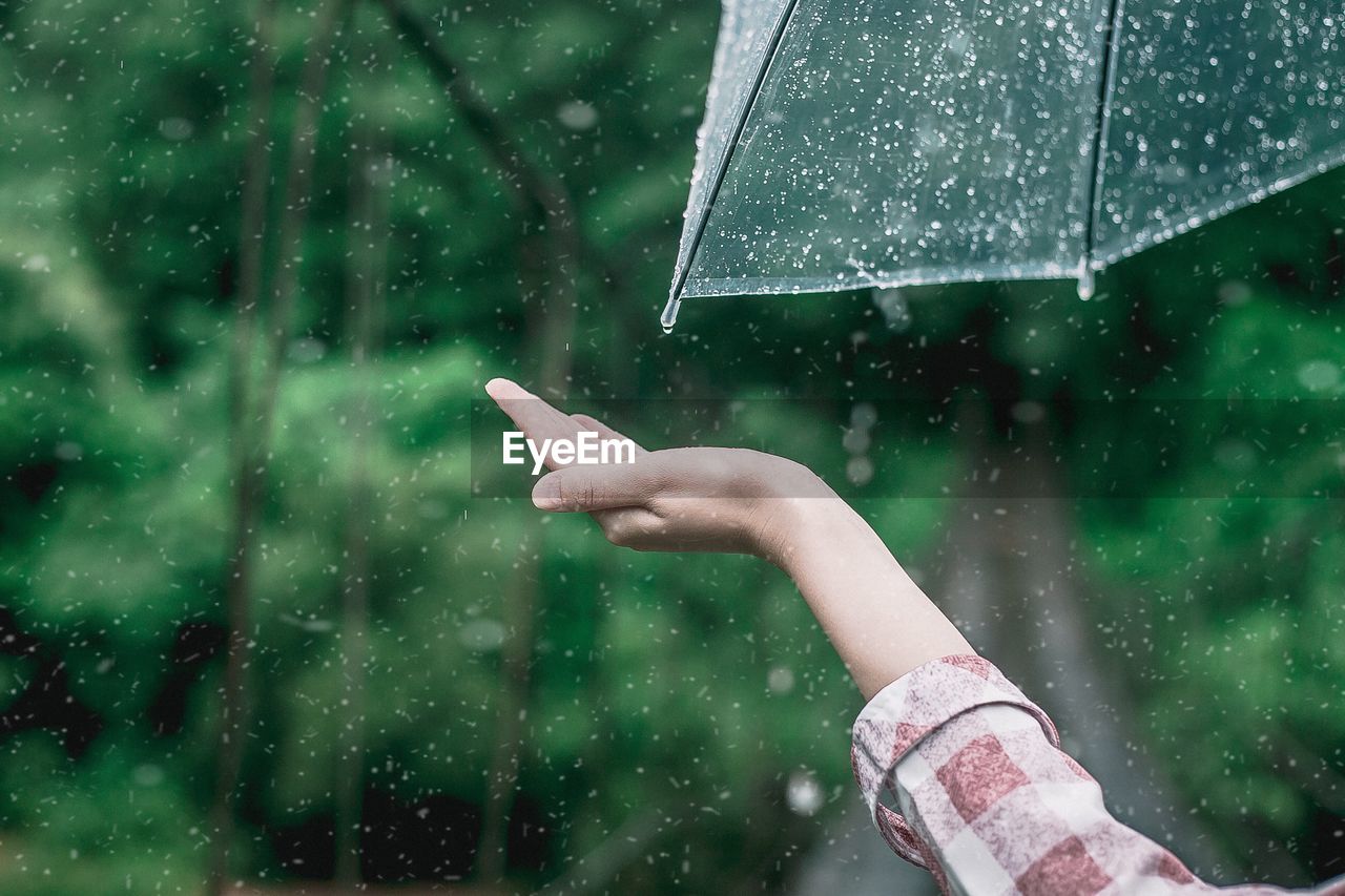 Hand holding wet glass during rainy season