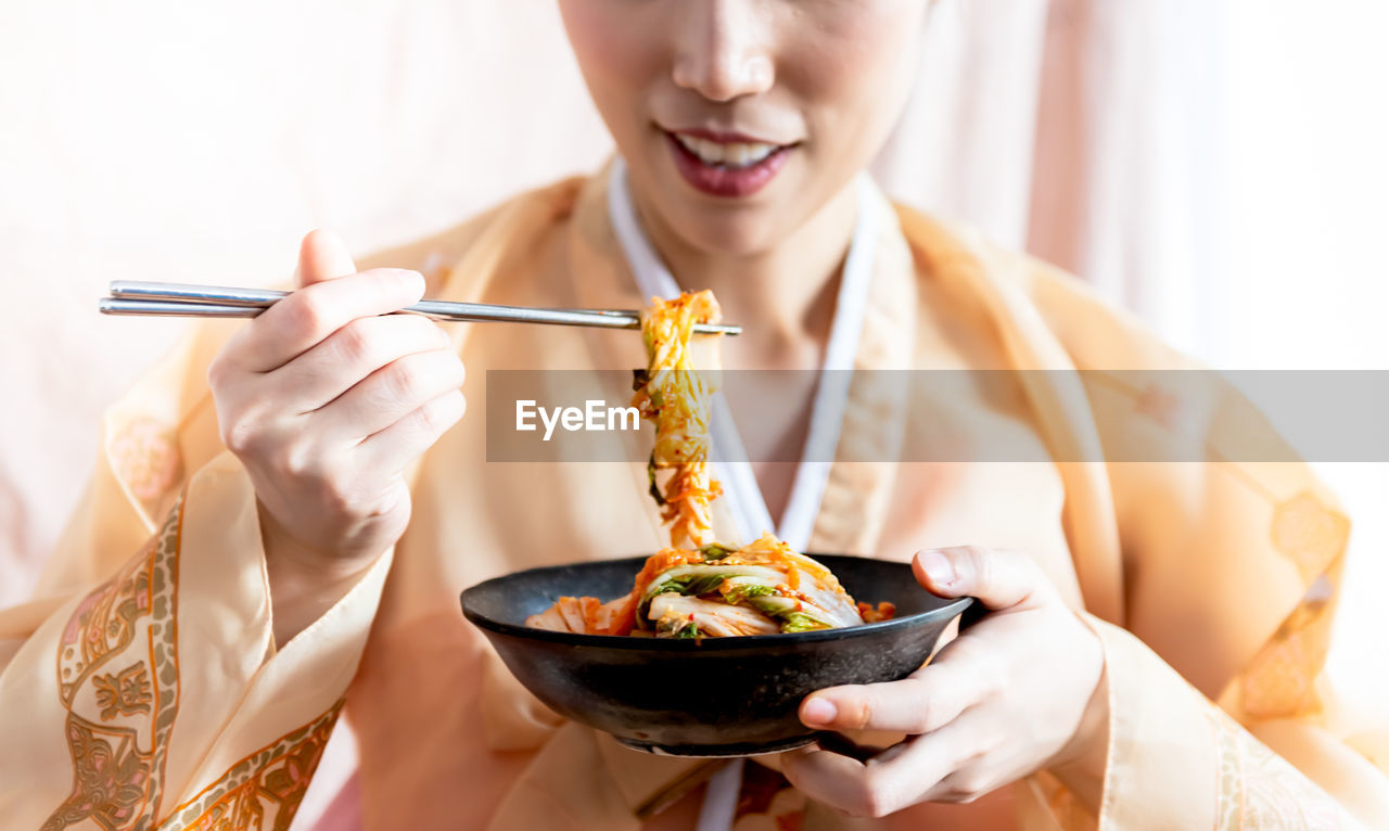 MIDSECTION OF WOMAN EATING NOODLES