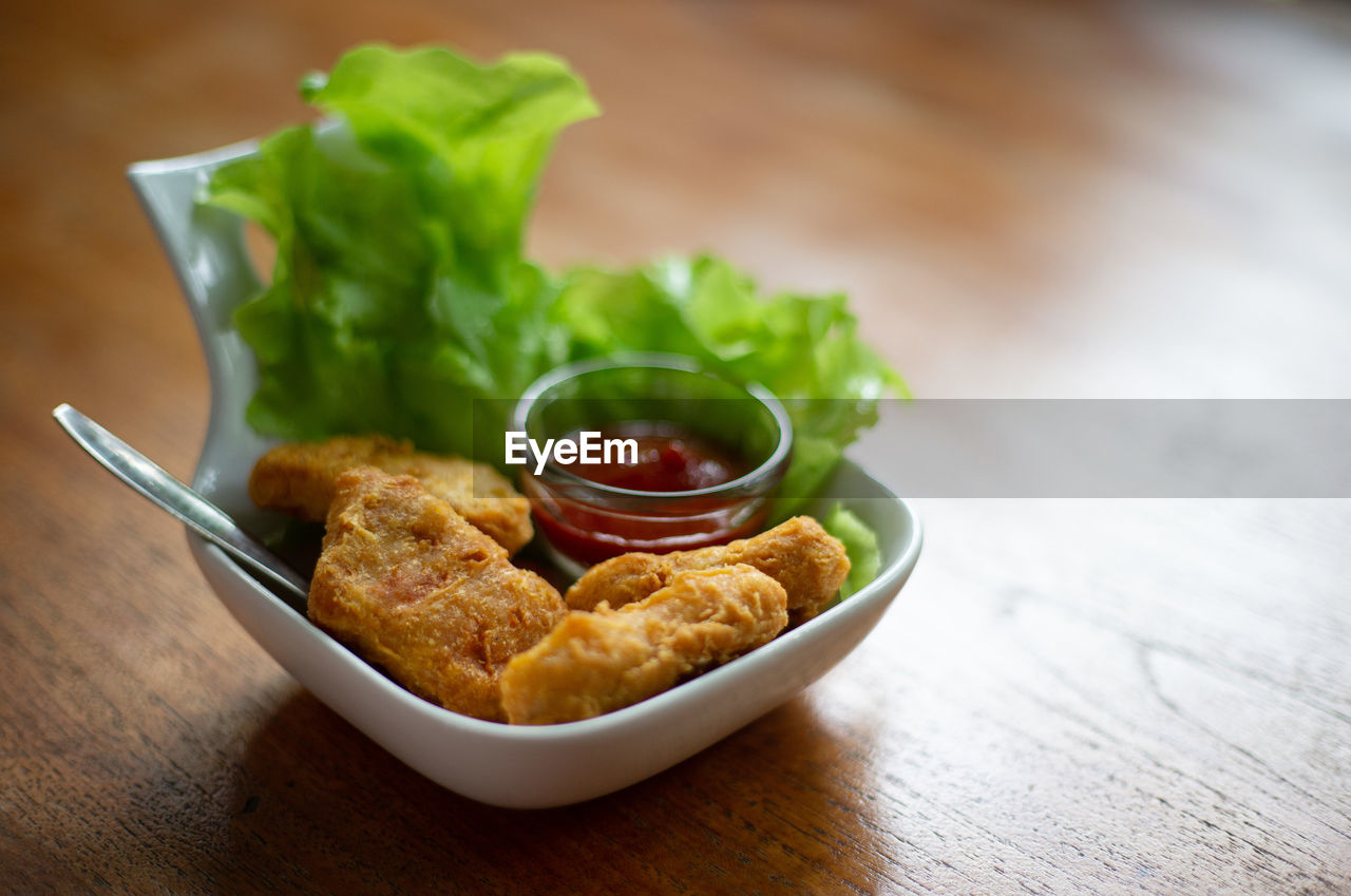 food and drink, food, healthy eating, fast food, vegetable, dish, freshness, wood, table, wellbeing, no people, bowl, indoors, meal, produce, asian food, meat, fried, cuisine, savory food, fried food, close-up, studio shot, plate, focus on foreground, appetizer, snack, eating utensil, chicken, salad, condiment, lettuce, spice