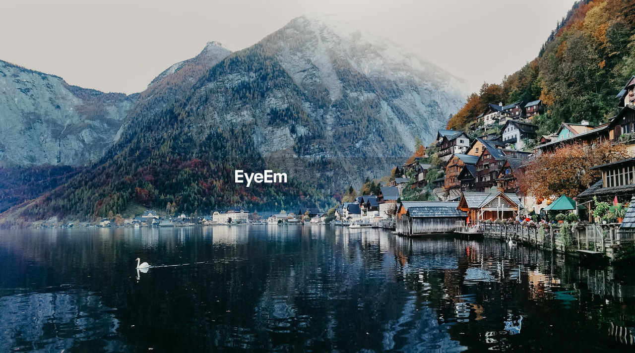 Town by lake and mountains against sky