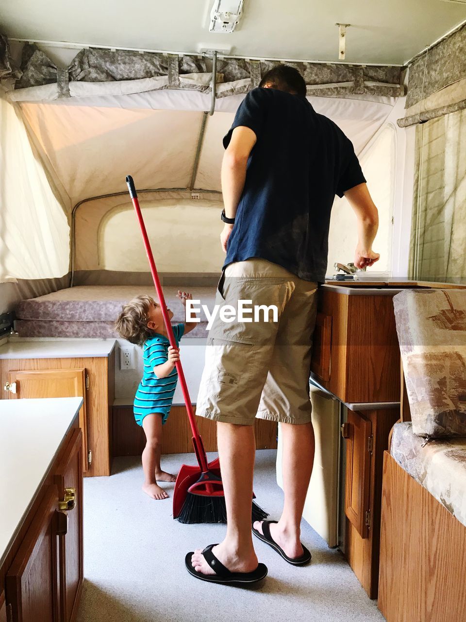 Full length of father and son cleaning bedroom