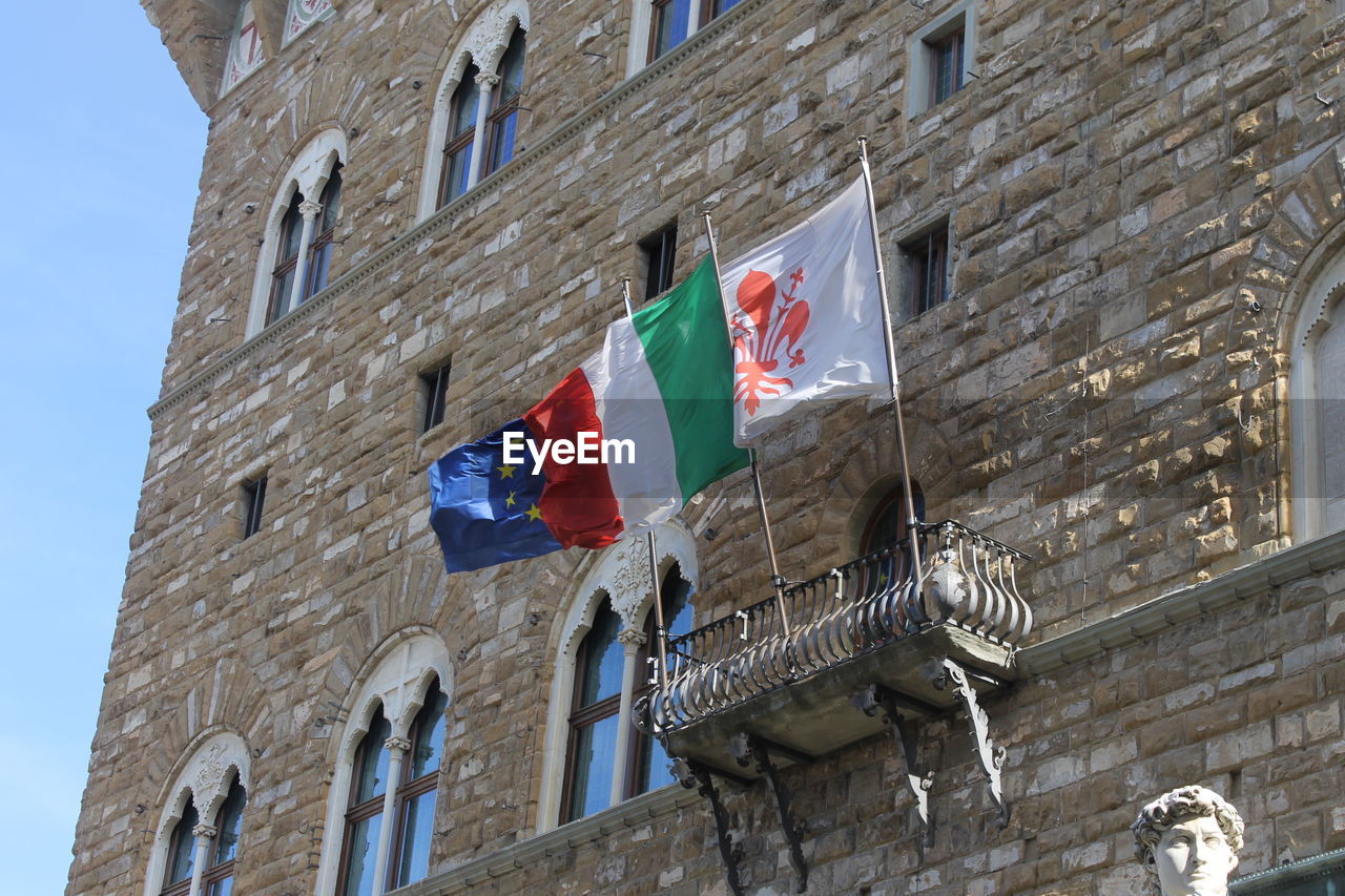 Low angle view of waving flags on palazzo vecchio