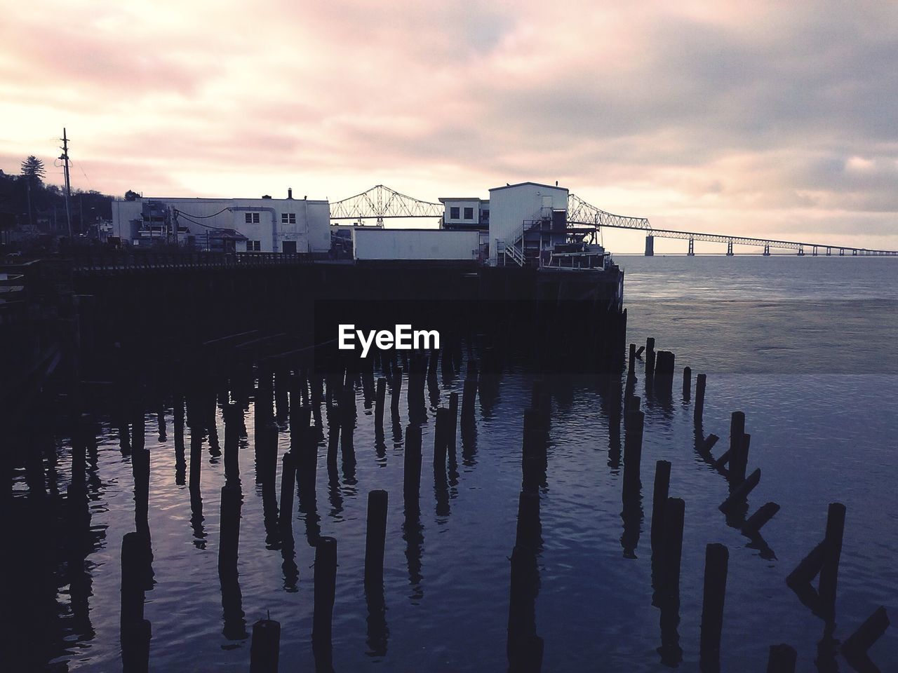 High angle view of silhouette wooden posts in sea at sunset