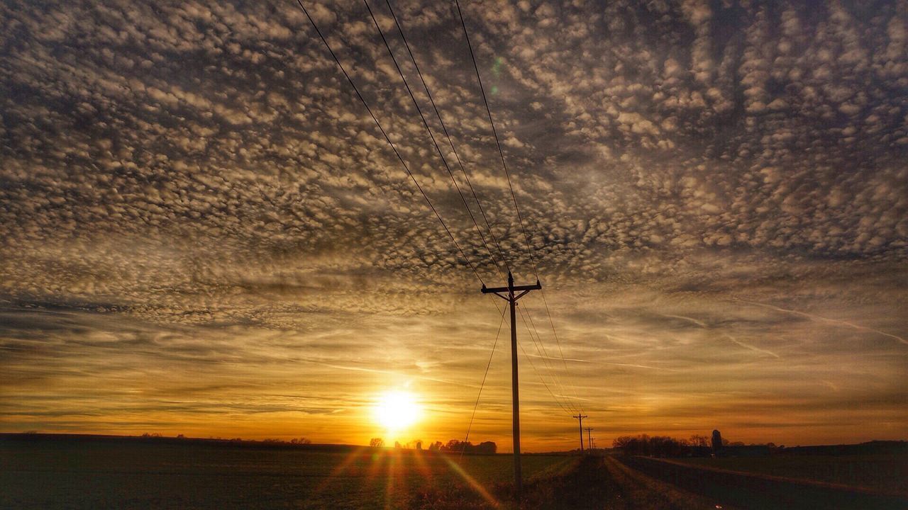 SILHOUETTE ELECTRICITY PYLON ON FIELD AGAINST SKY AT SUNSET