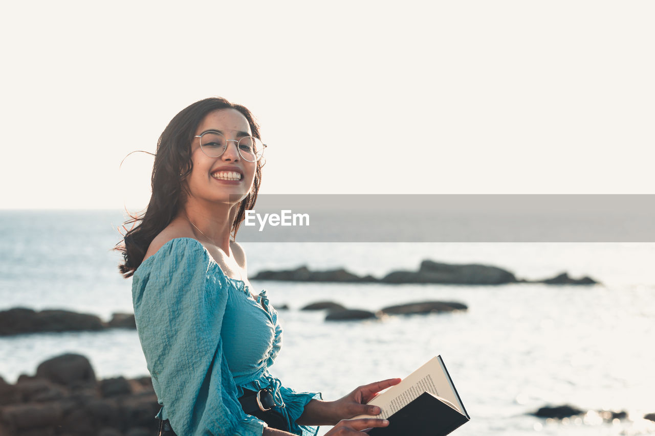 Portrait of young woman using phone on beach