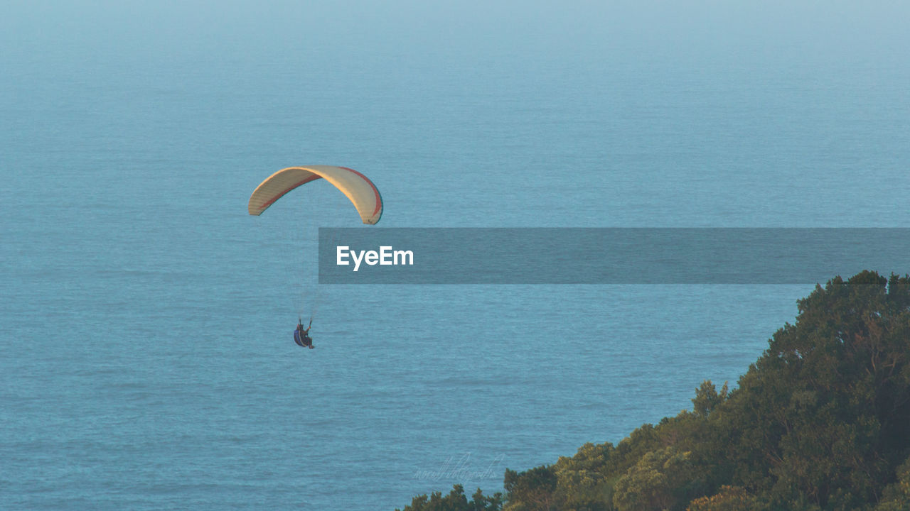 Low angle view of person paragliding over sea