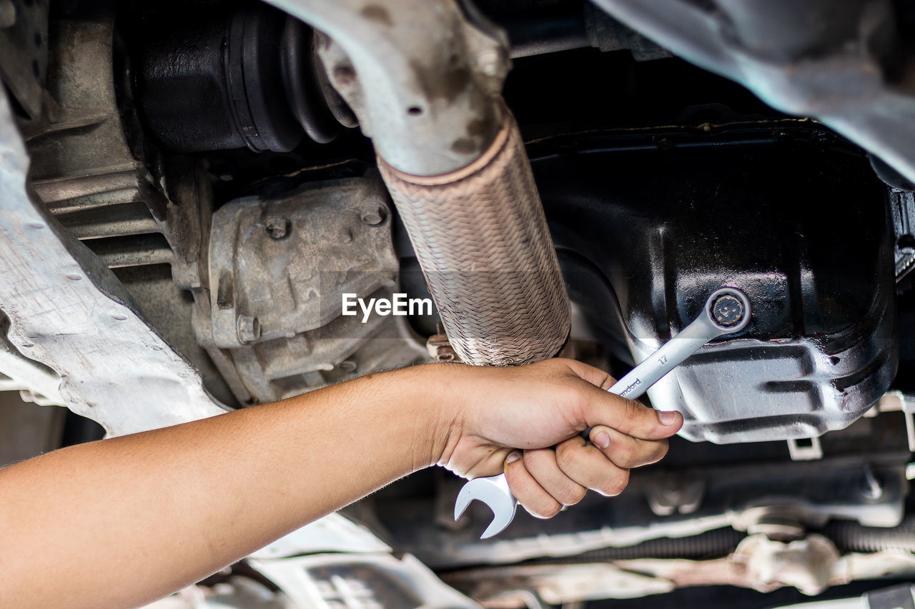 Cropped hand of mechanic repairing car in auto repair shop