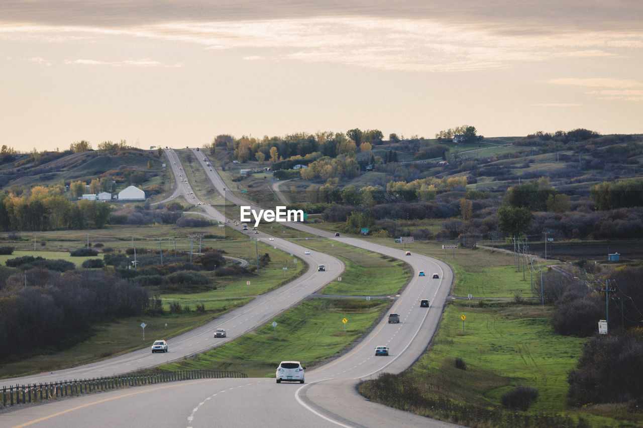 HIGH ANGLE VIEW OF VEHICLES ON ROAD AGAINST SKY