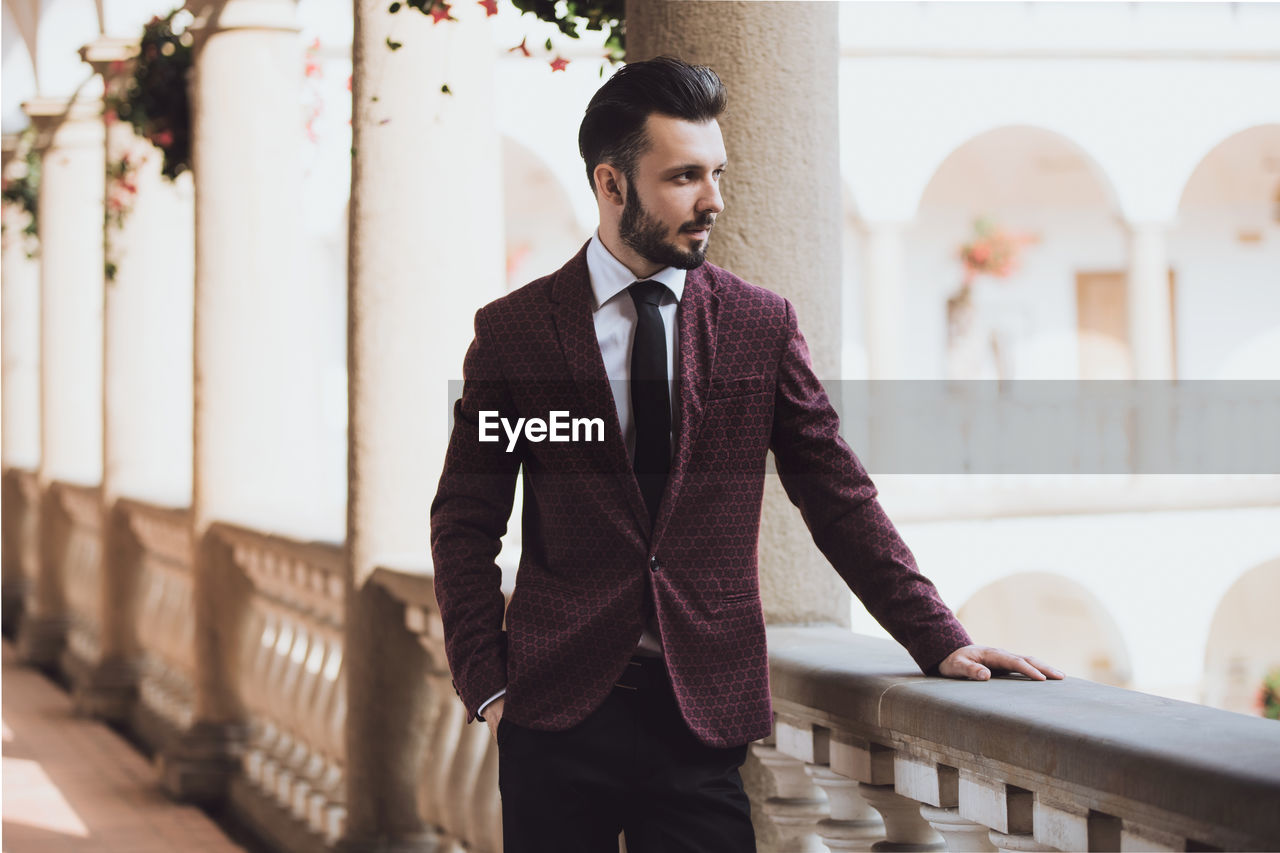 Well-dressed thoughtful man looking away while standing in corridor