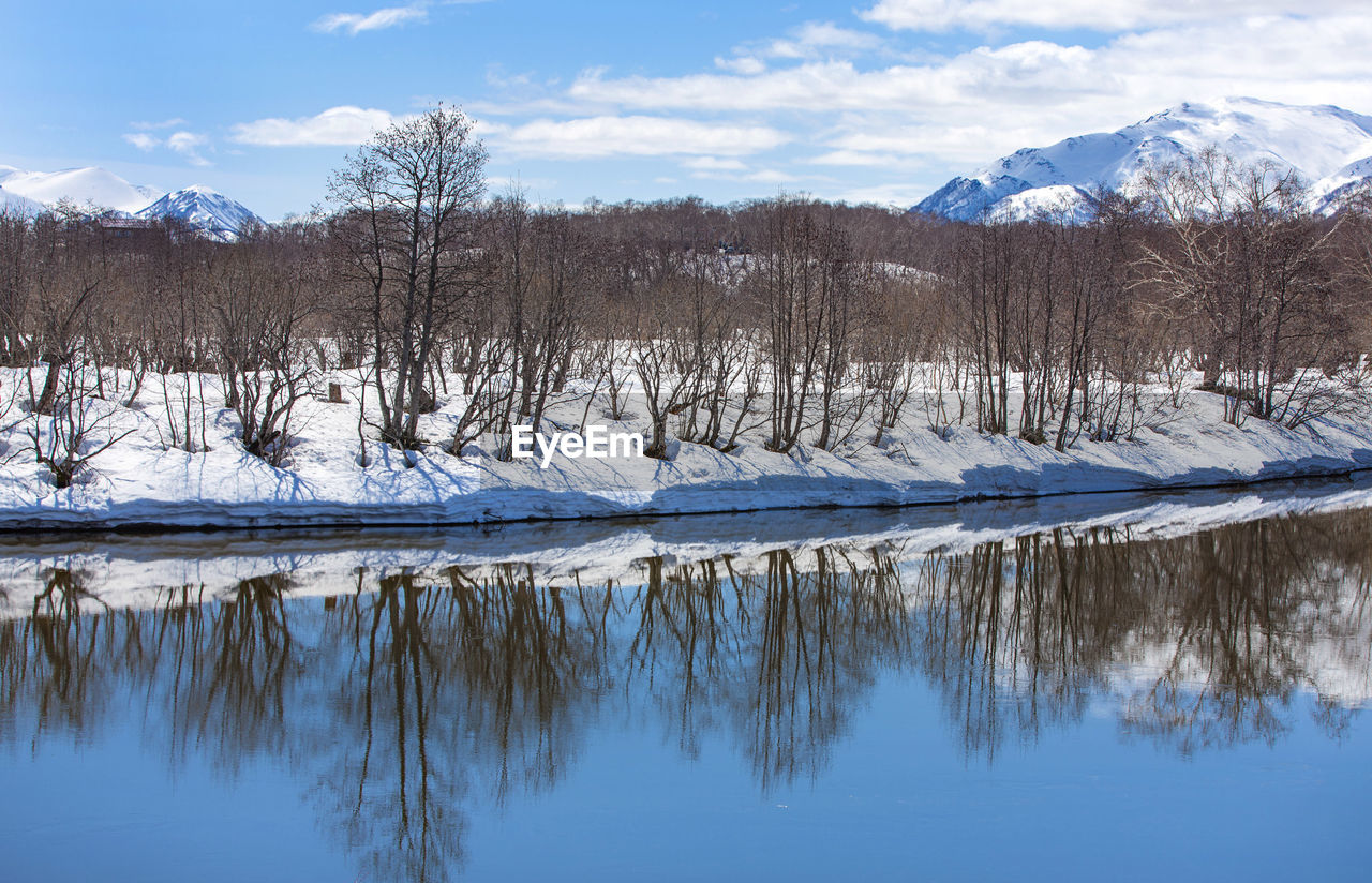 River, volcano, snow-covered forest and blue sky in early spring