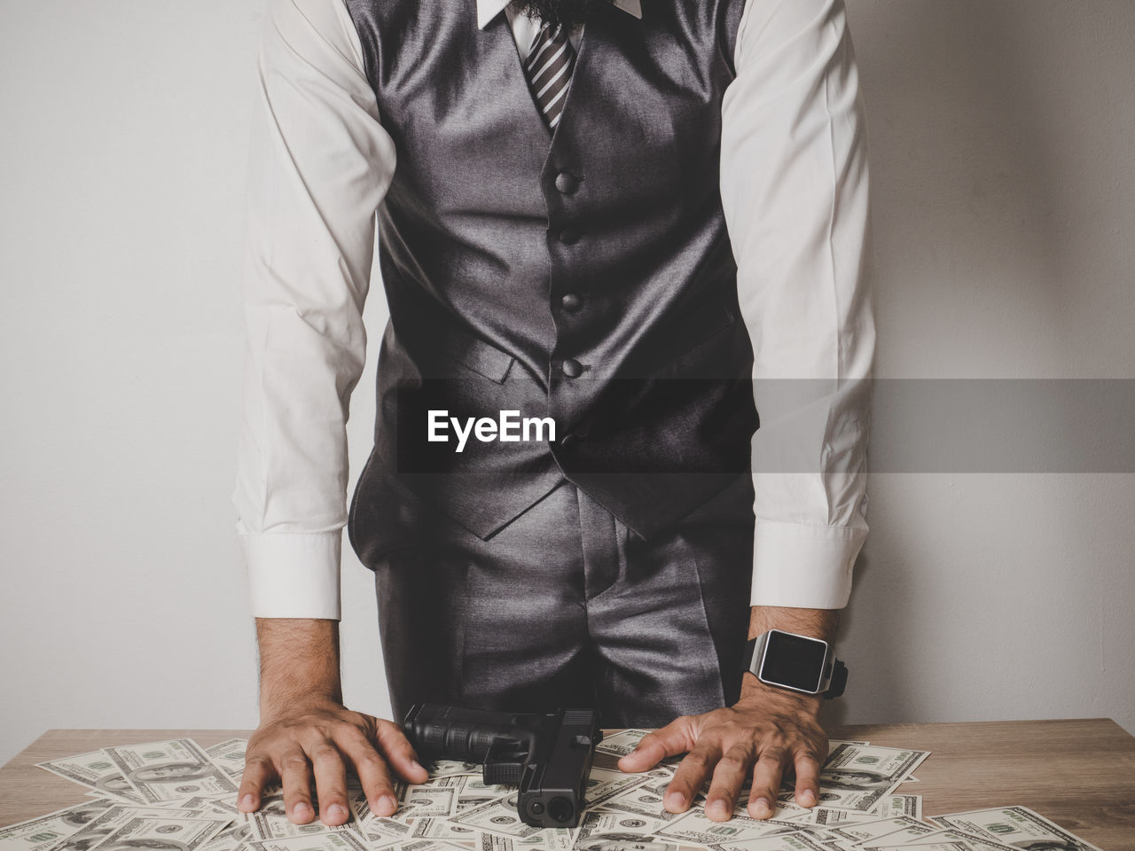 Midsection of businessman with paper currencies and gun