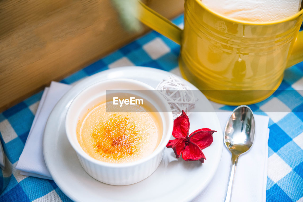 A portion of delicate creme brulee in ramekin on the table on a checkered napkin