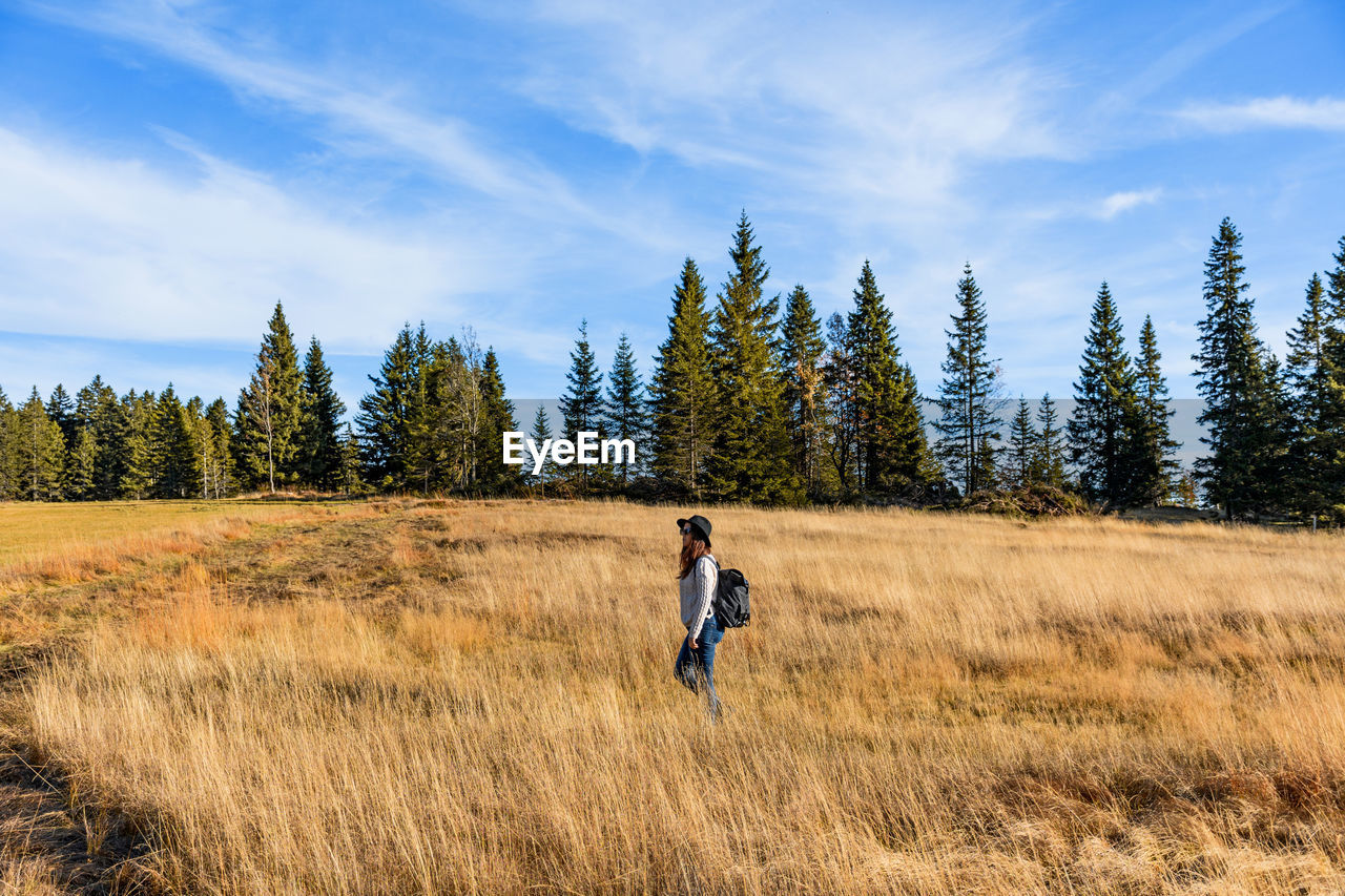 Young woman hiking through a field of golden tall grass.