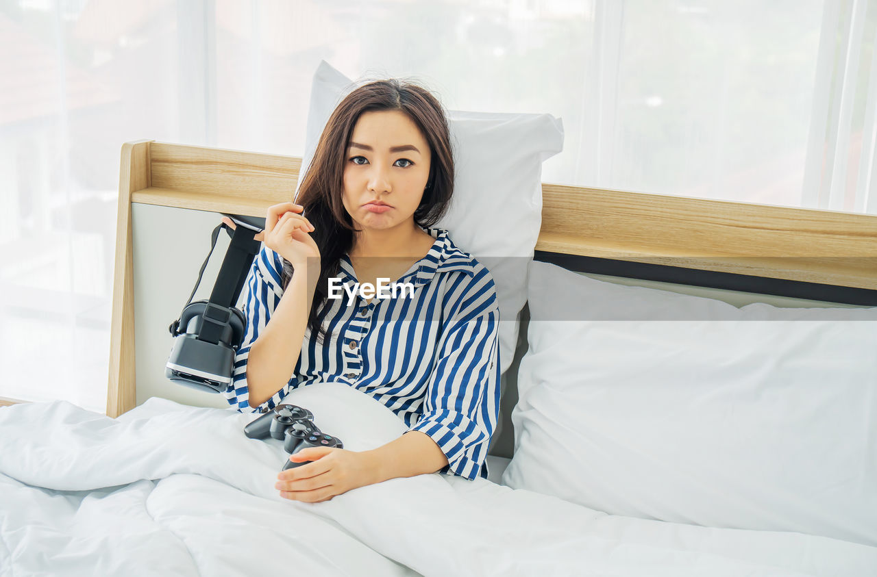 PORTRAIT OF YOUNG WOMAN LYING ON BED IN BEDROOM