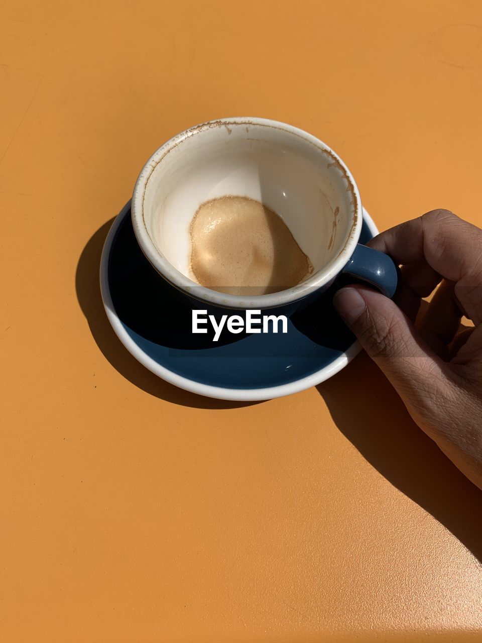 COFFEE CUP ON TABLE AGAINST ORANGE WALL