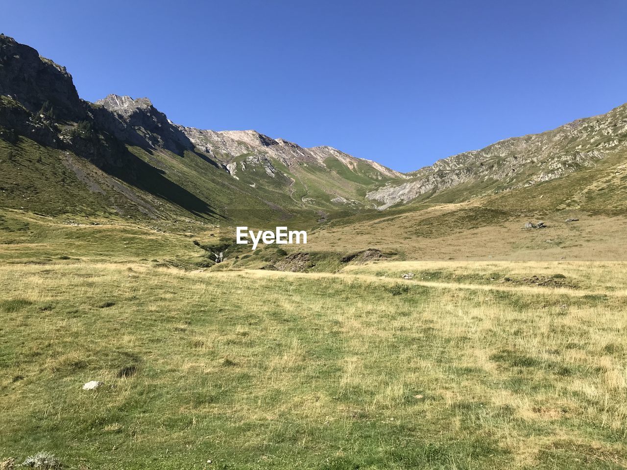 Scenic view of landscape and mountains against clear blue sky