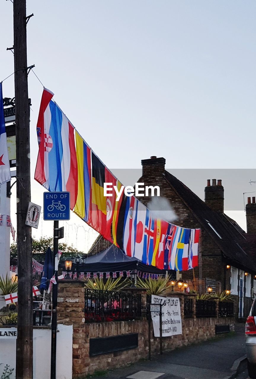 LOW ANGLE VIEW OF FLAGS HANGING AGAINST BUILT STRUCTURE