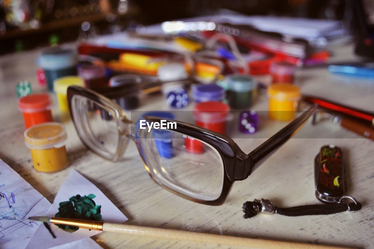 Close-up of eyeglasses with paints on table