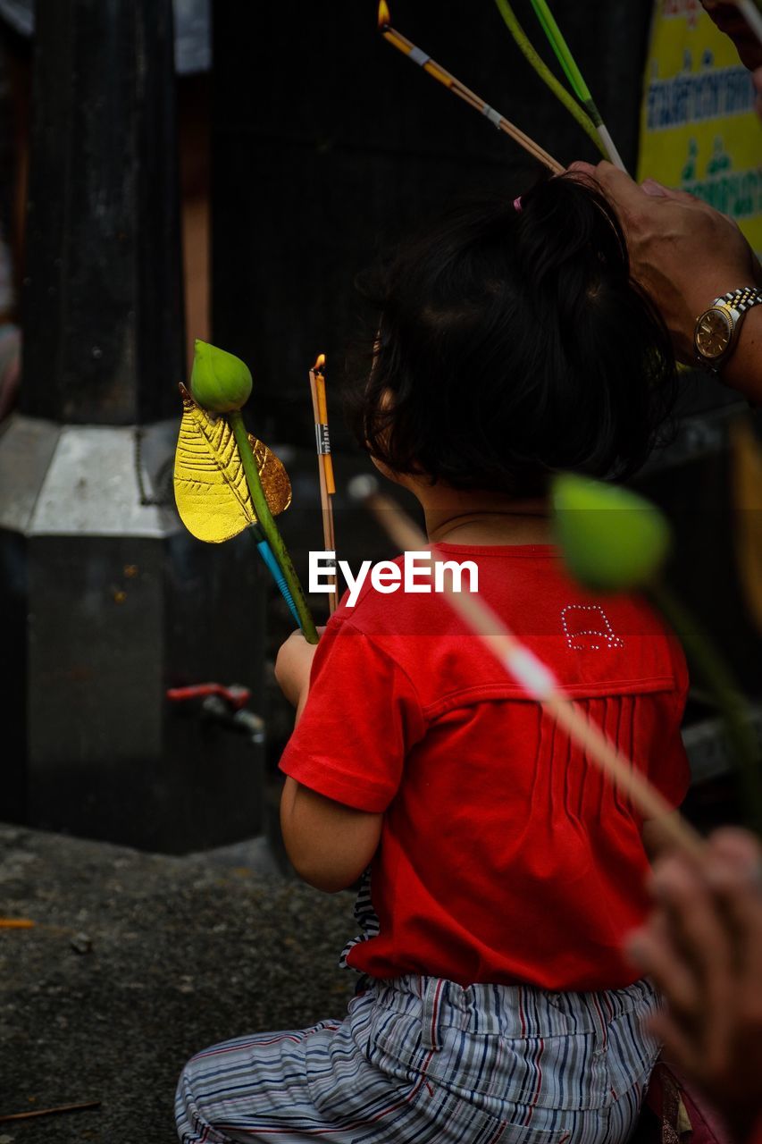 Rear view of girl holding religious equipment