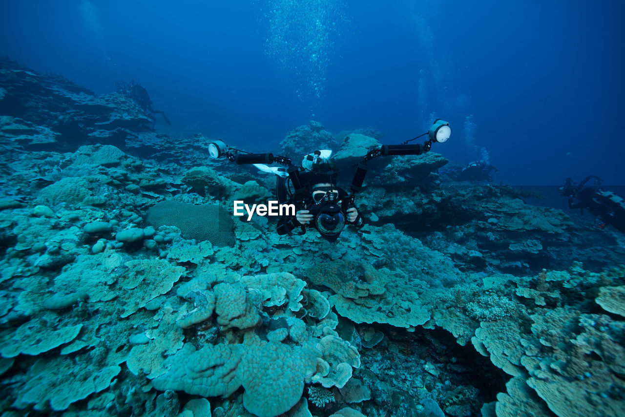 High angle view of scuba divers swimming in blue sea