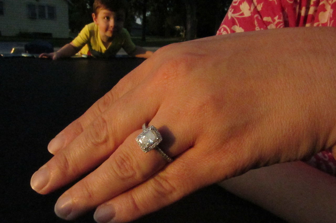 Woman showing engagement ring while boy is looking