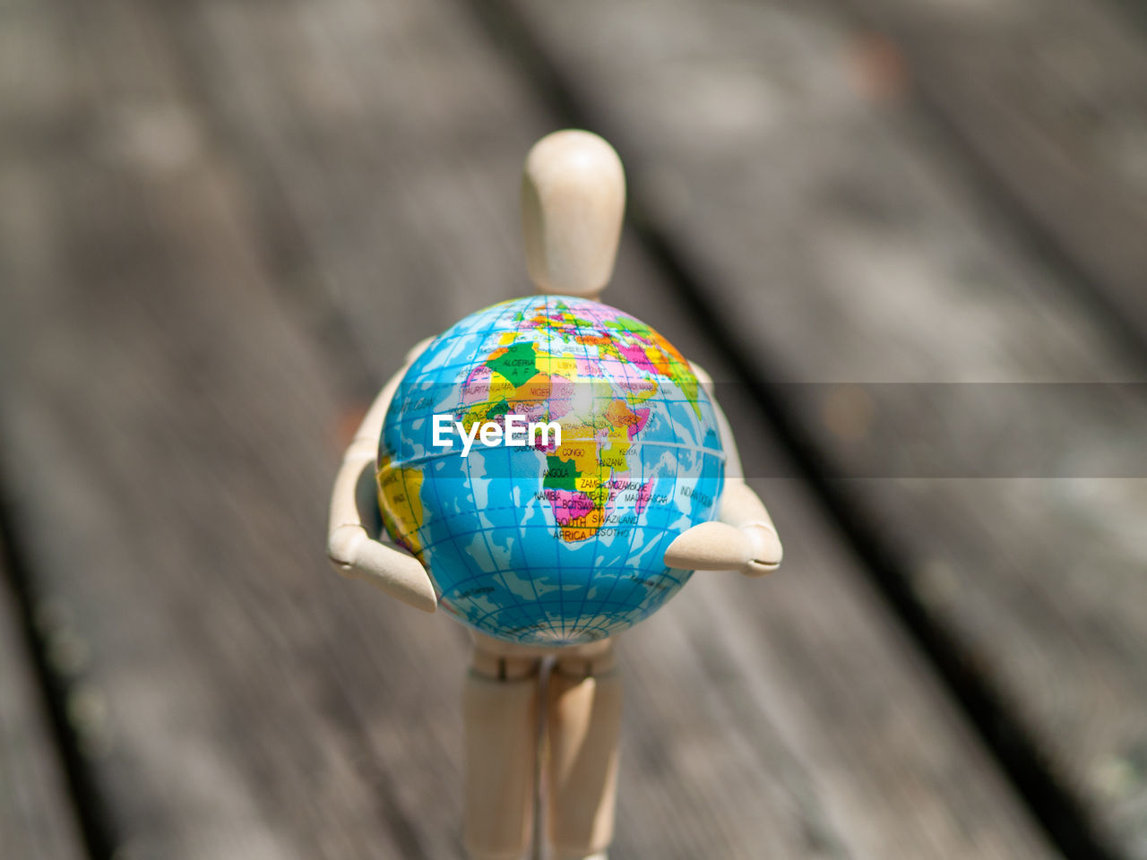 Close-up of wooden figurine holding globe on table