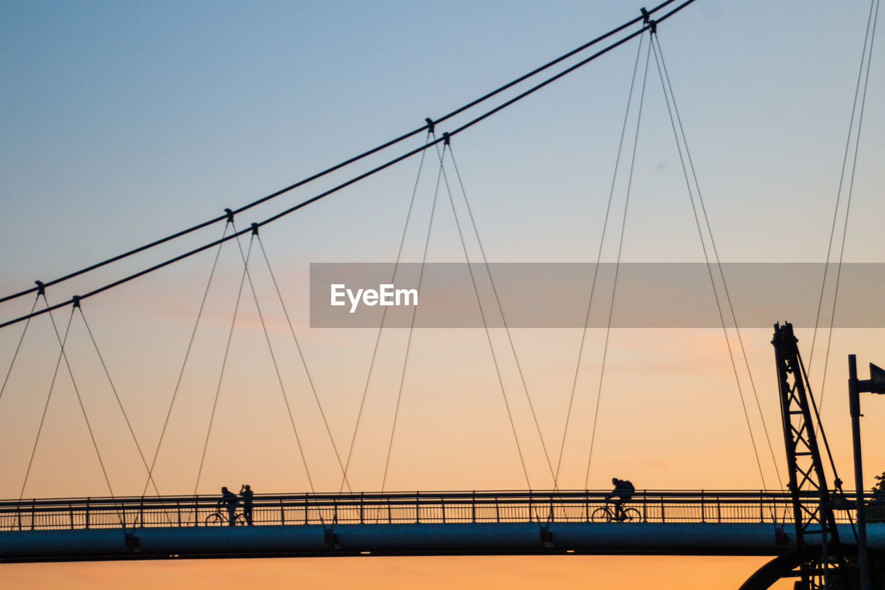 Silhouette people on bridge against sky during sunset