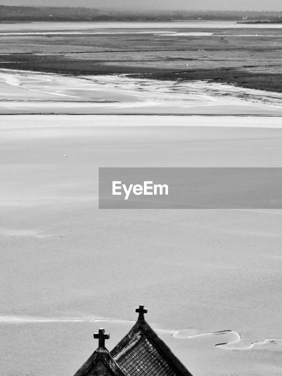 Cross on roof of mont saint-michel against snow covered landscape