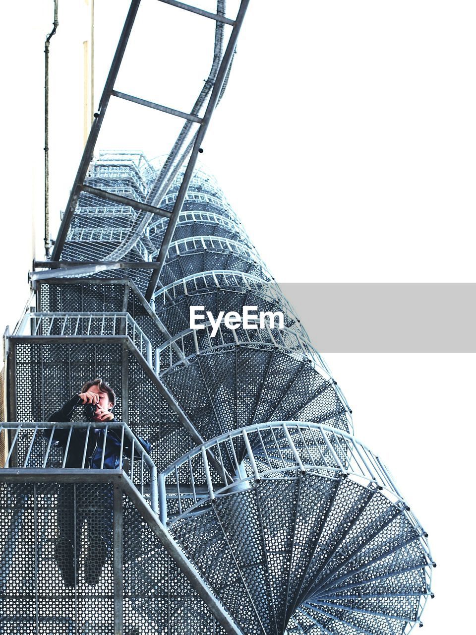 Low angle view of man holding camera while standing on steps in building