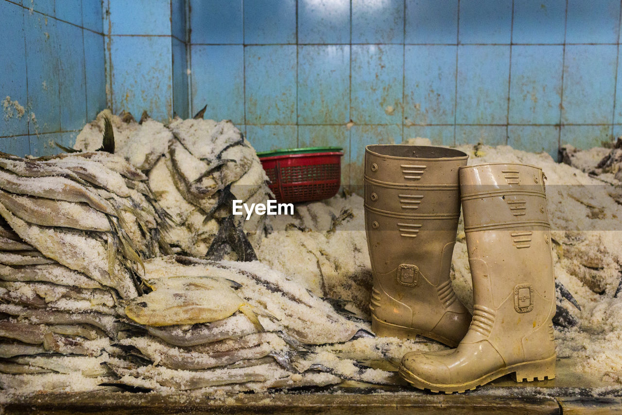 Rubber boots by ice on stacked fish at table