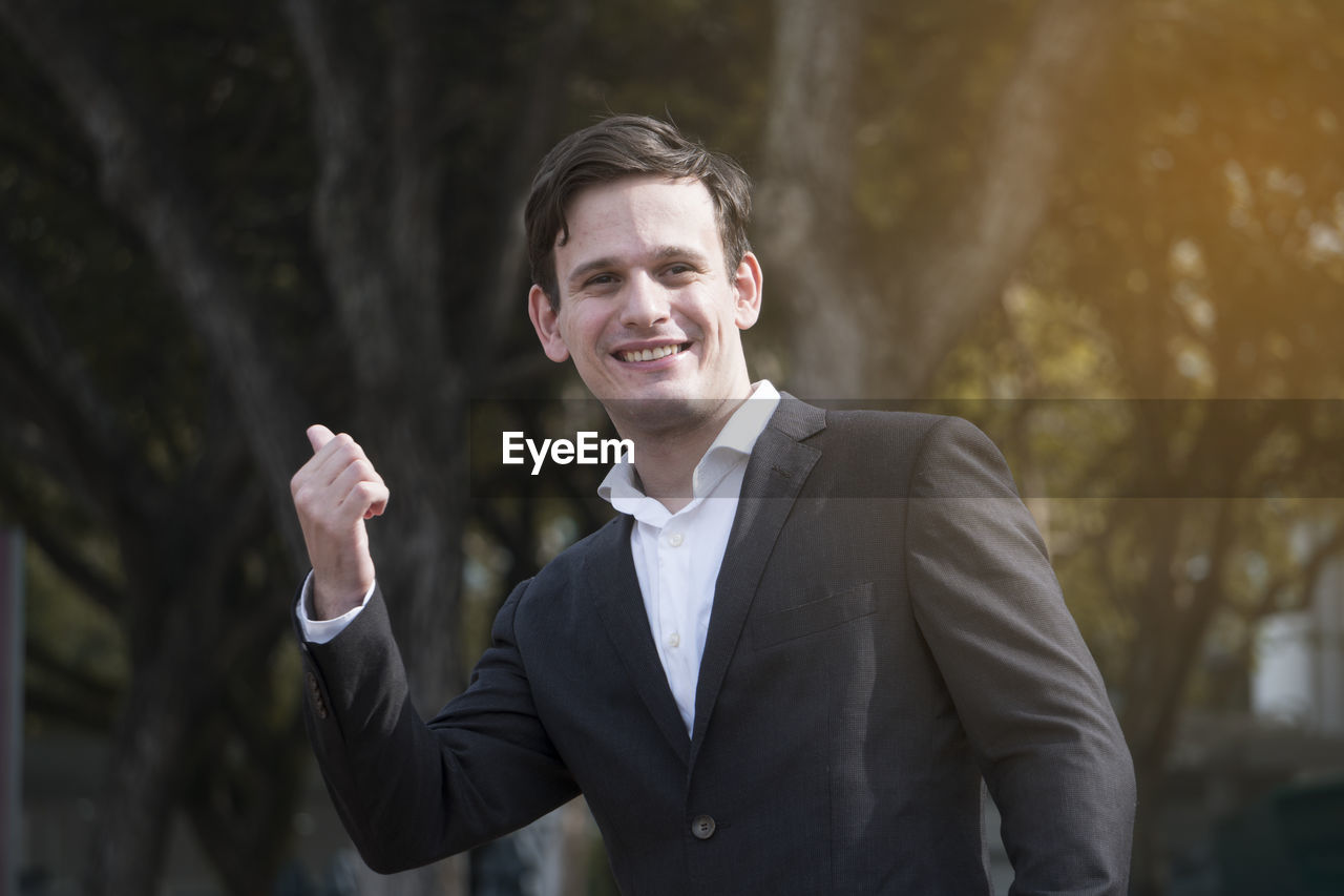 Portrait of businessman gesturing on sunny day