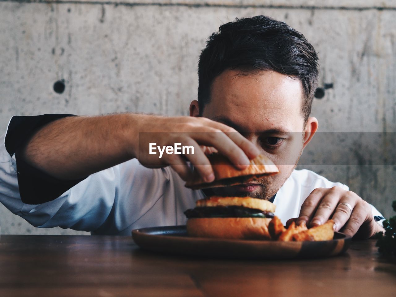 Close-up of chef preparing burger at table