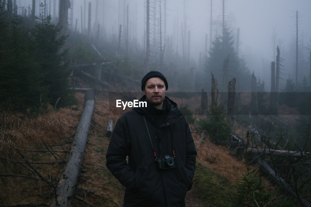 Portrait of young man standing in forest