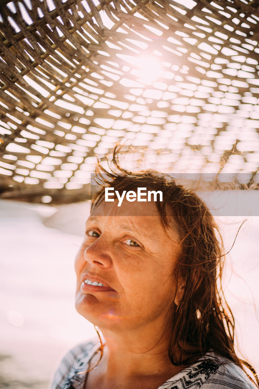 Adult caucasian woman relaxed posing under beach umbrella on sunset. vacation on sea ocean.