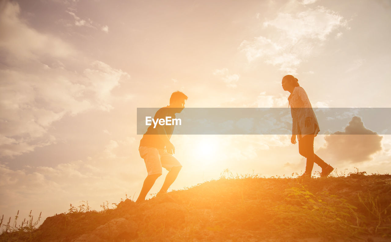 FRIENDS STANDING ON LAND AGAINST SKY