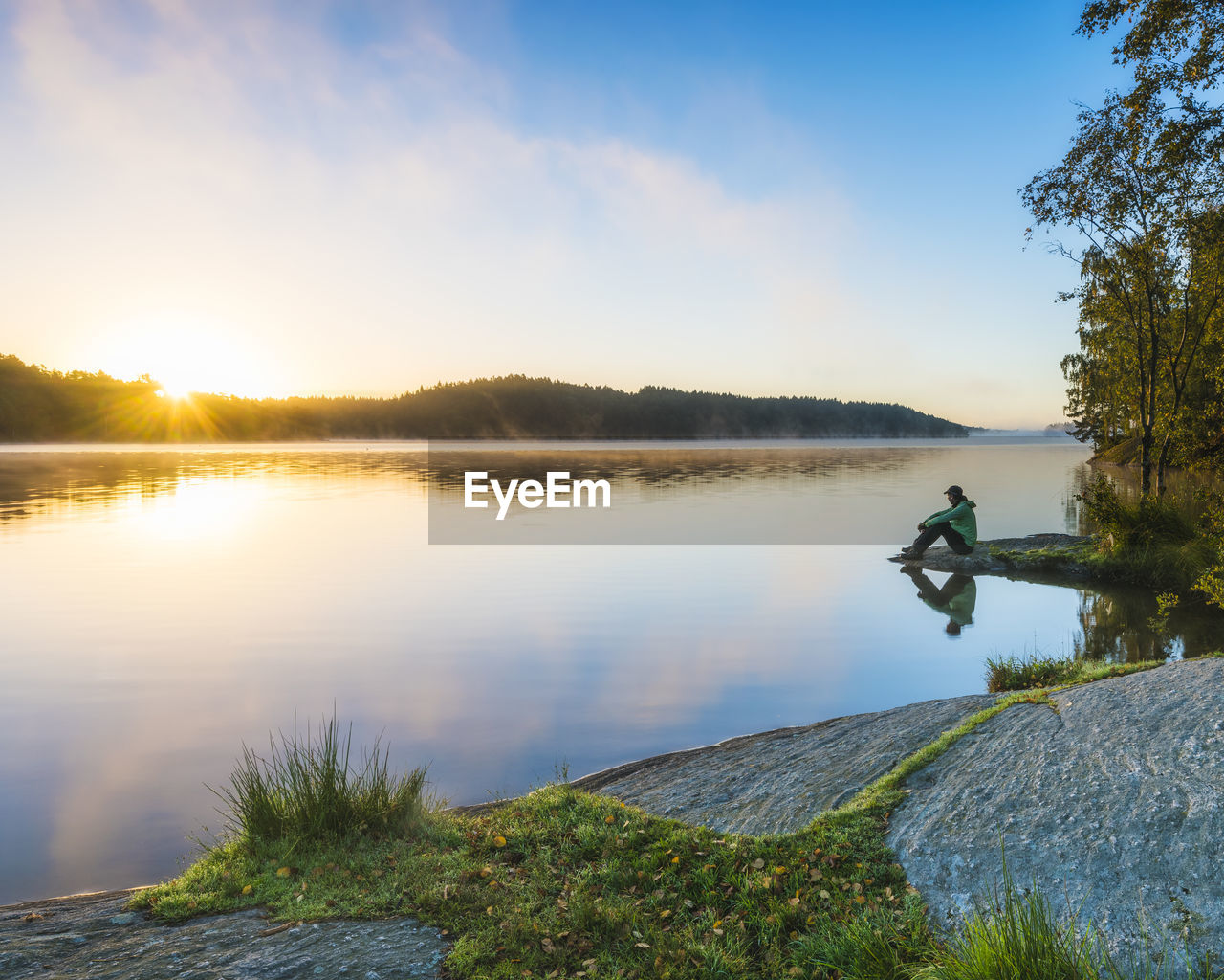 Person at lake looking at sunset