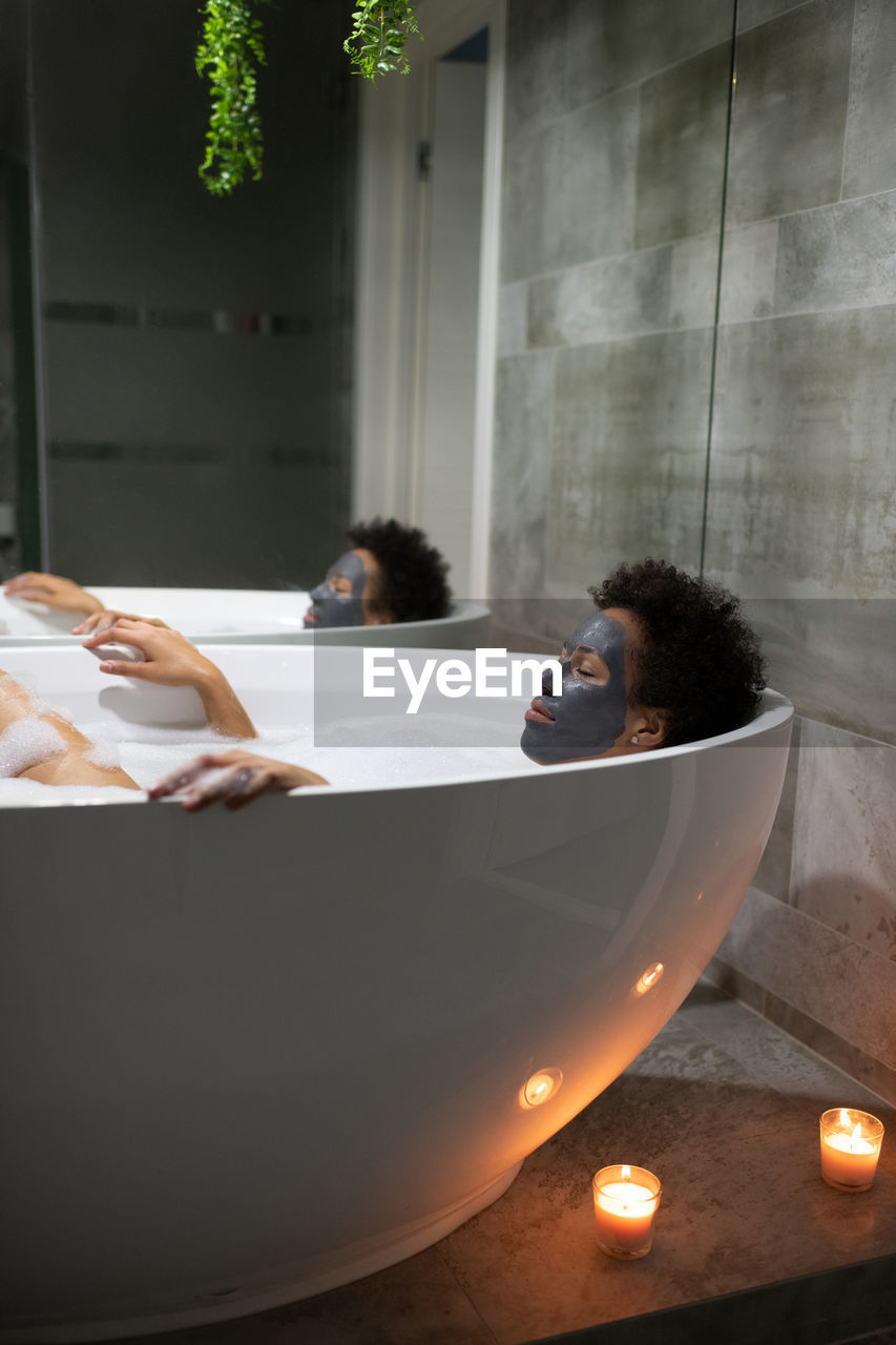 Mixed race female resting in bathtub