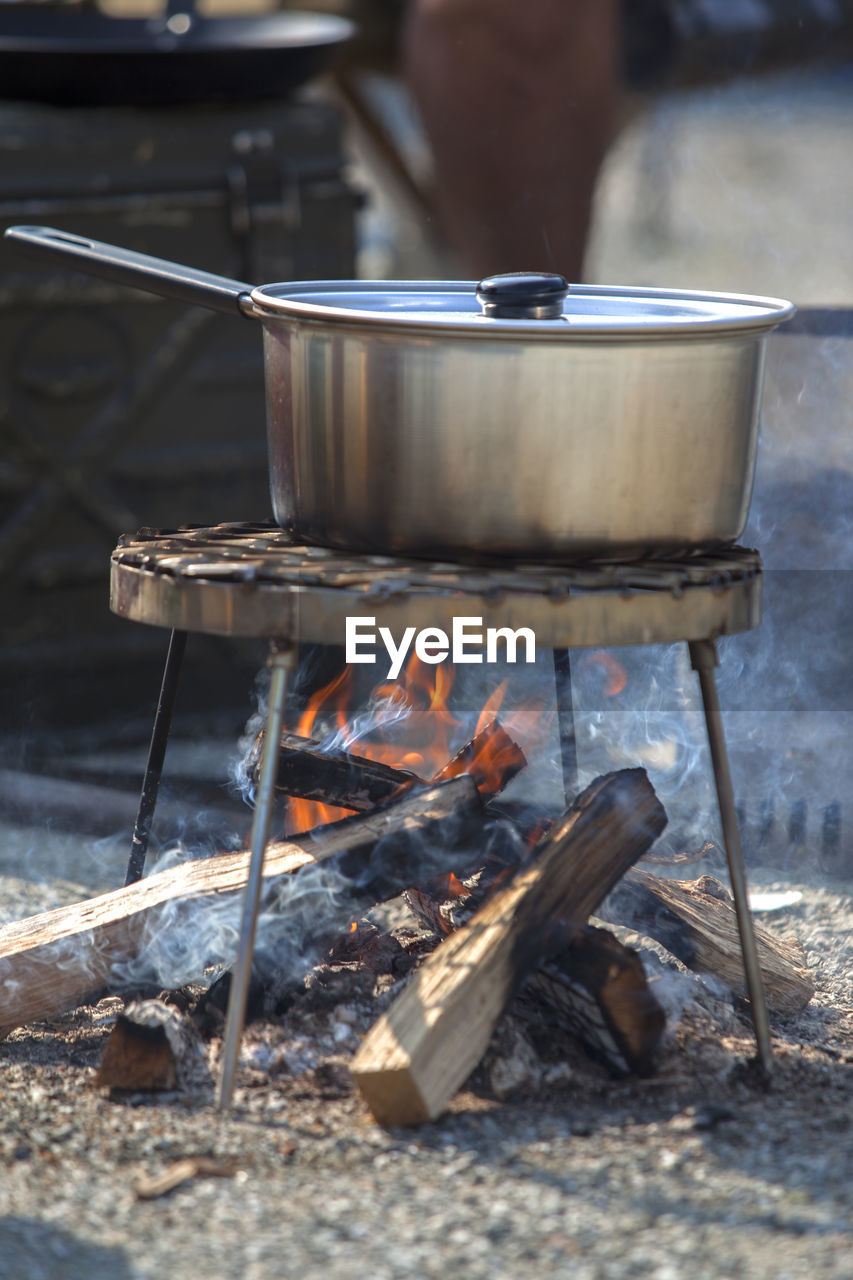 Food cooking in saucepan on metal grate at campsite
