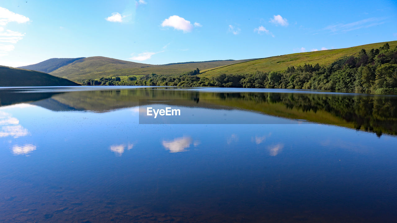 reflection, water, scenics - nature, lake, sky, beauty in nature, mountain, environment, reservoir, tranquility, nature, landscape, tranquil scene, blue, no people, body of water, land, cloud, travel destinations, tree, non-urban scene, wilderness, plant, mountain range, day, travel, outdoors, idyllic, forest, tourism, morning