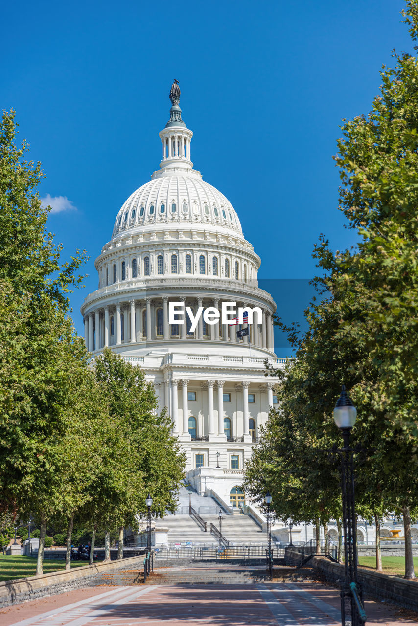 dome, government, landmark, architecture, building exterior, tree, built structure, plant, politics, city, authority, flag, no people, travel destinations, nature, building, day, travel, courthouse, tower, sky, outdoors, neo-classical