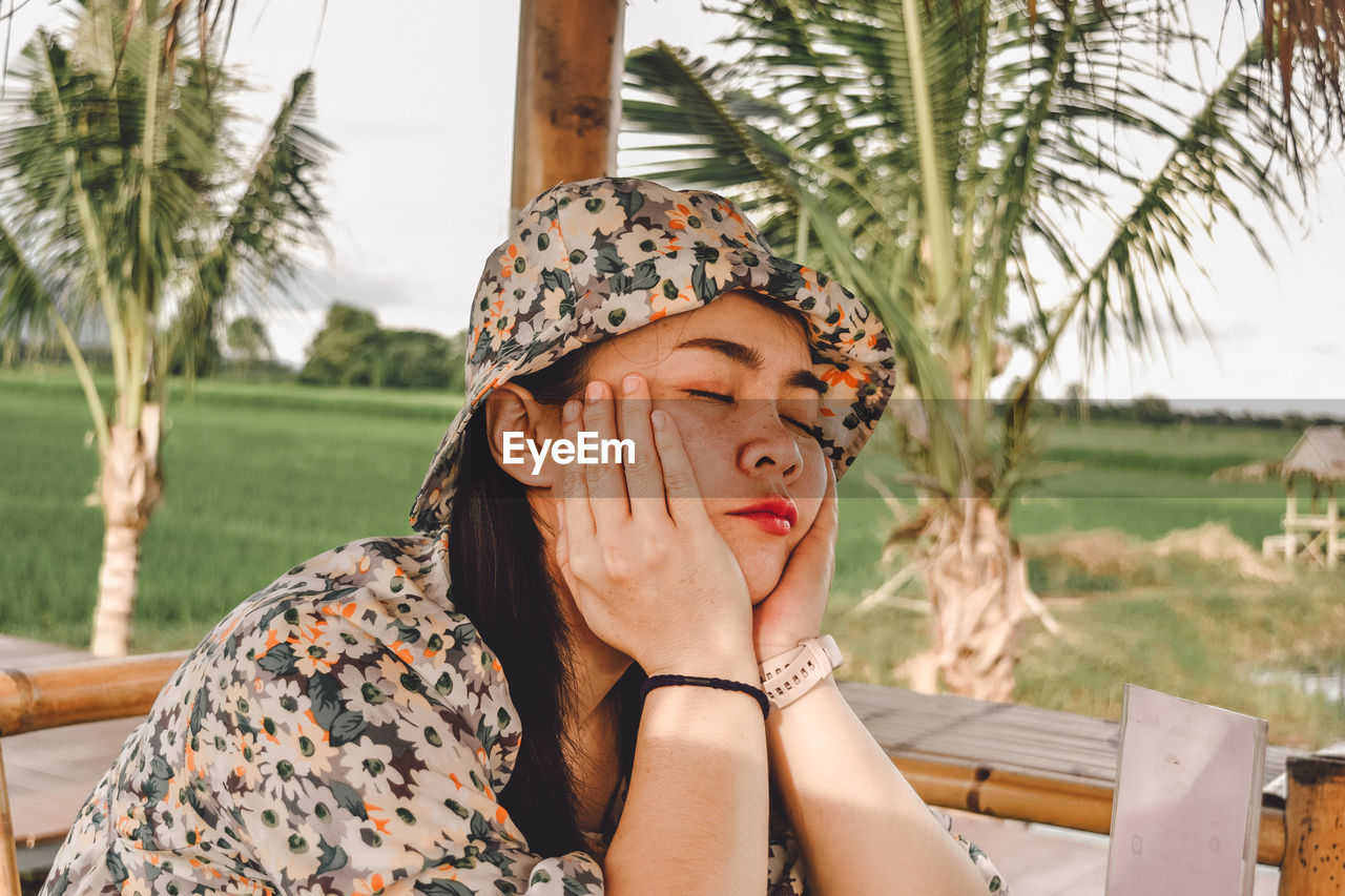 Portrait of young woman sitting on palm tree