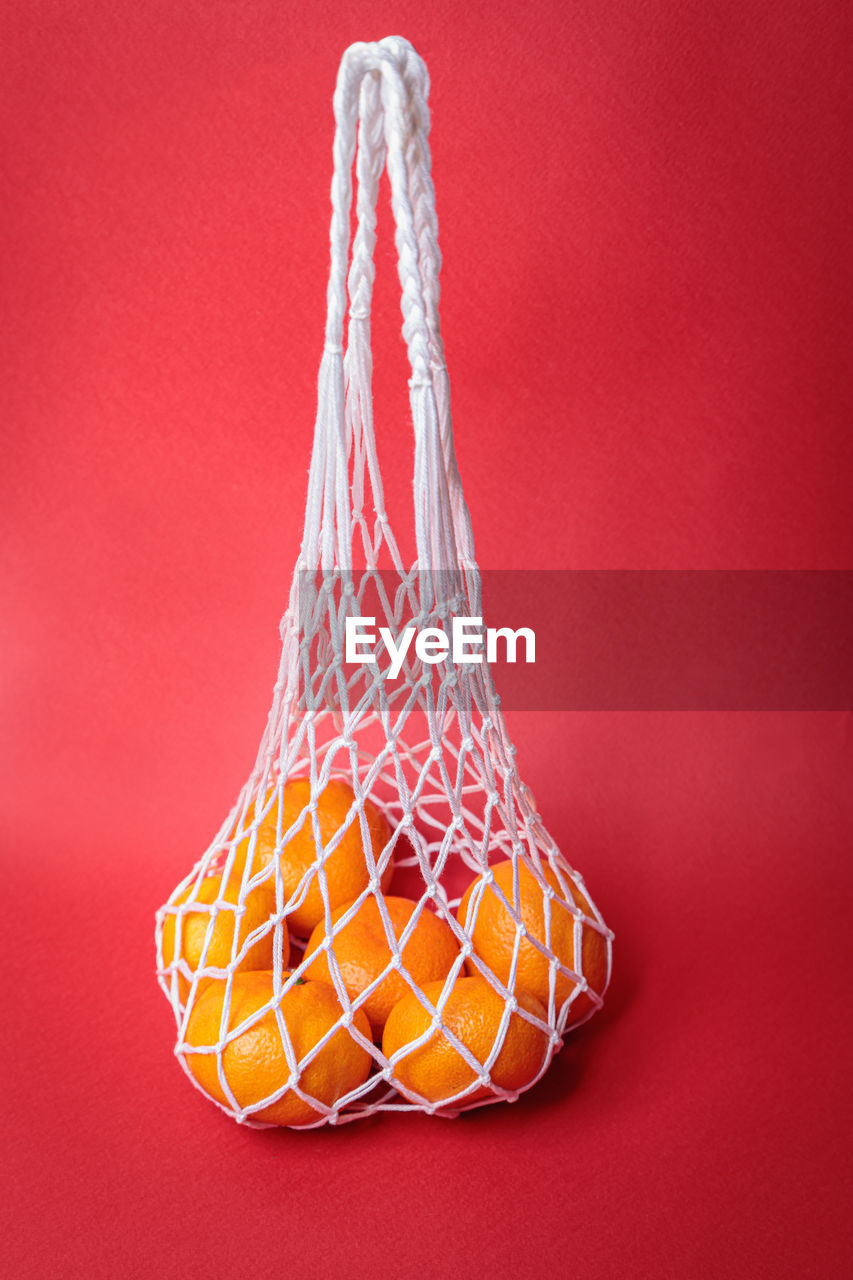 Eco-friendly mesh with tangerines on a red festive background. feast of the nativity of christ.