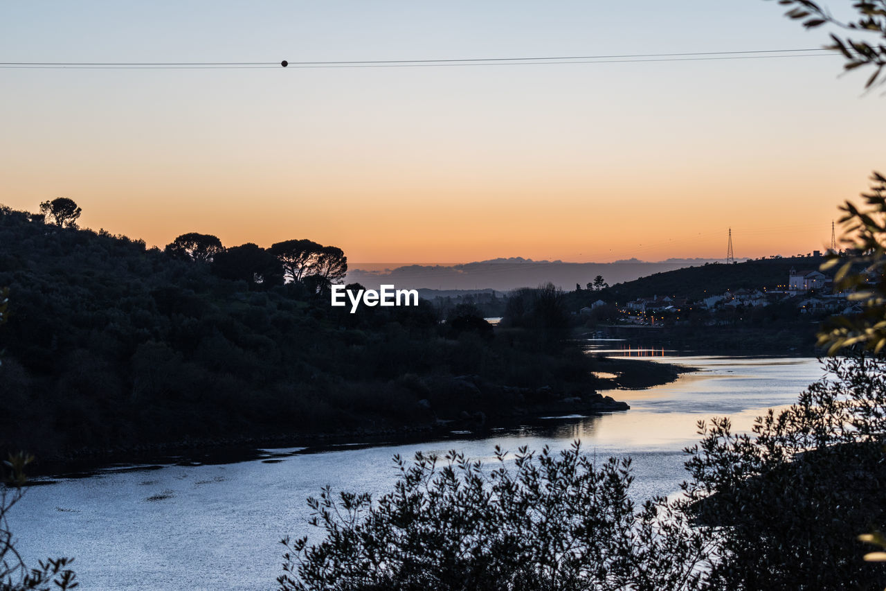 SCENIC VIEW OF RIVER BY SILHOUETTE TREES AGAINST SKY