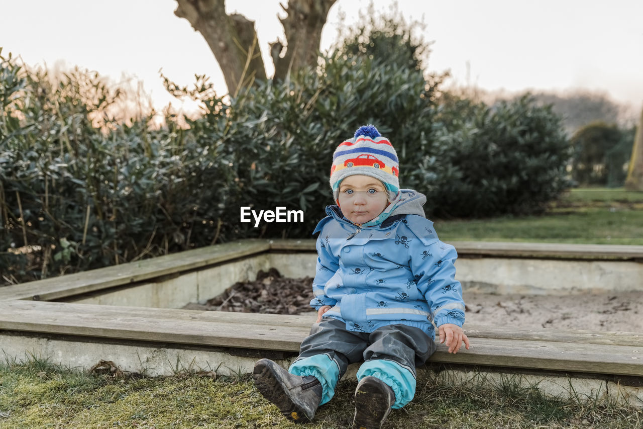 Portrait of cute boy wearing knit hat against trees