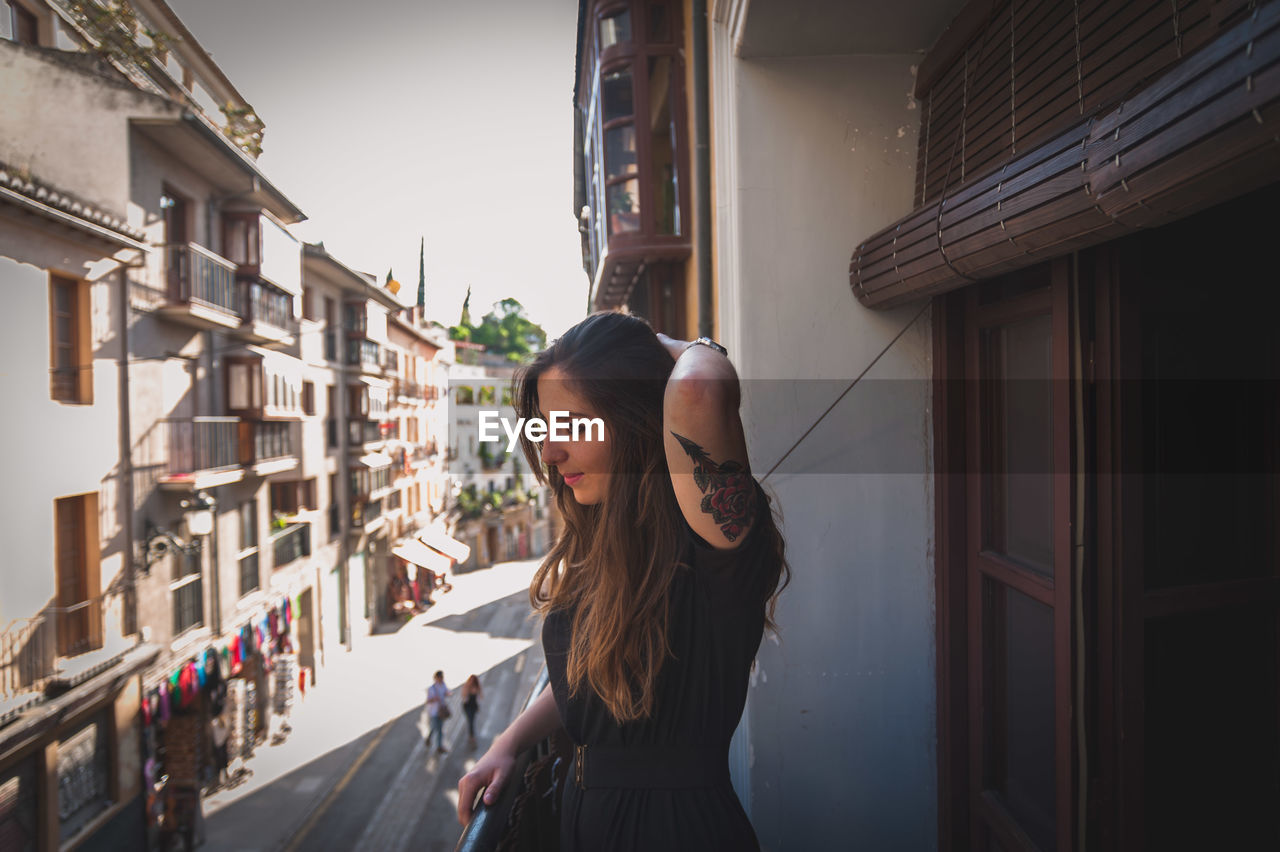 Beautiful woman with hand in hair standing in balcony