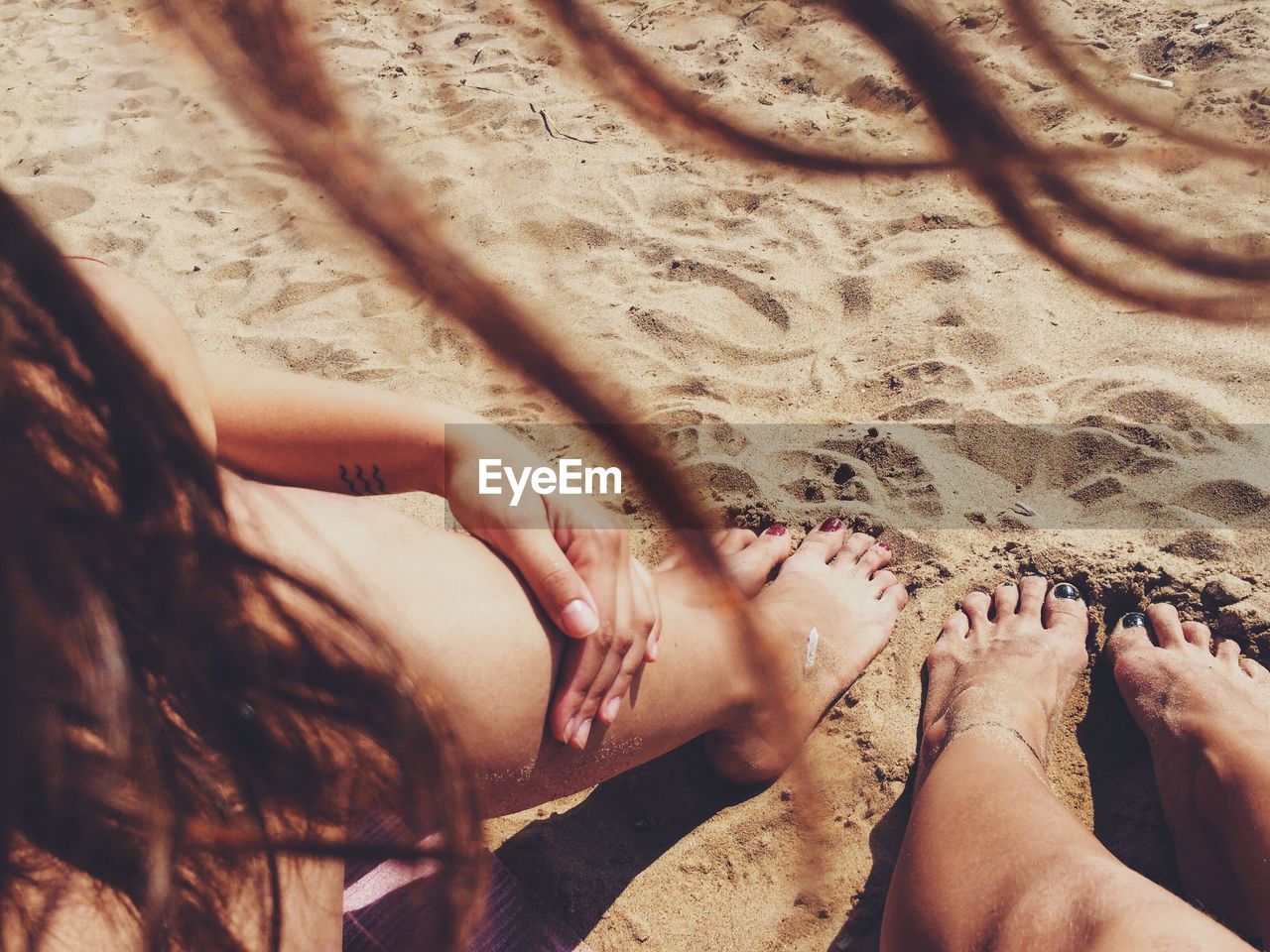 Low section of woman on sand at beach