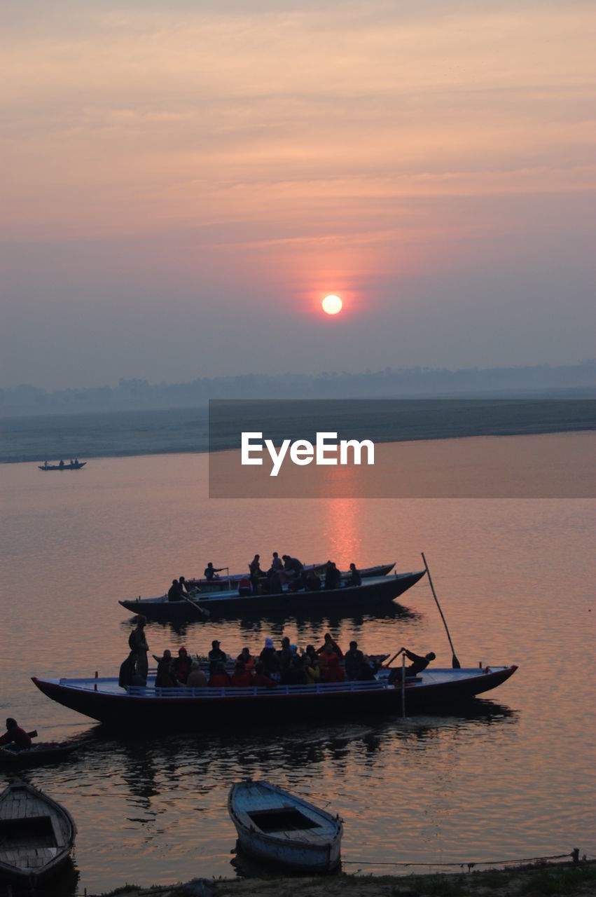 Boat moored on sea against sky during sunset