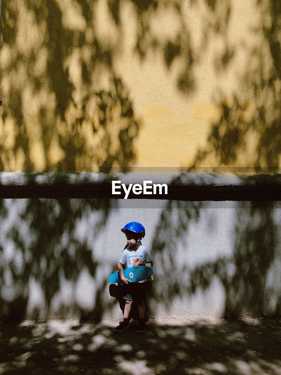 A boy in a helmet with a skateboard in his hands near the wall